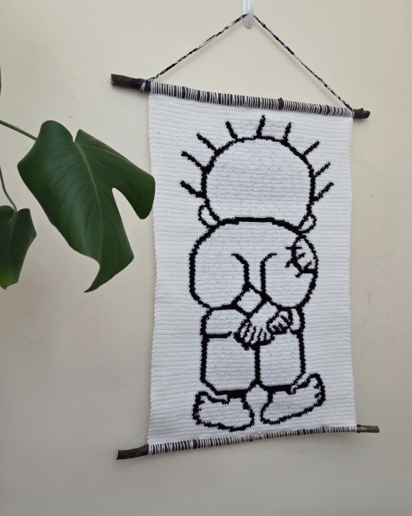 crochet tapestry with cartoon figure of Handala